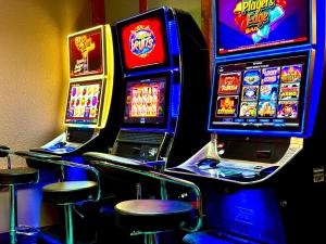 a row of slot machines in a casino with stools at Lacombe Motor Inn in Lacombe