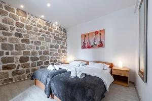 two beds in a room with a stone wall at Welcome Apartment - Old Town in Dubrovnik