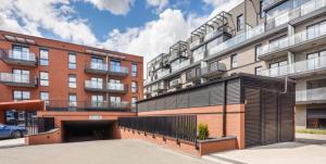 an apartment building with a parking lot in front of it at Welcome Gdańsk Apartaments Nadmotławie Gym and Sauna in Gdańsk