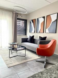a living room with a couch and a red chair at Saffron Place @ 2bed Apt Midrand in Midrand