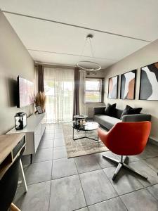 a living room with a couch and a red chair at Saffron Place @ 2bed Apt Midrand in Midrand