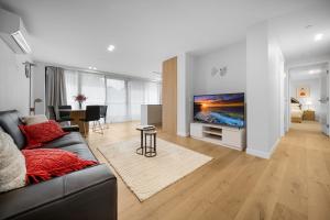 uma sala de estar com um sofá e uma televisão de ecrã plano em Elegant 2-Bed by Lyneham Wetlands near the CBD em Camberra