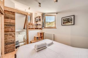 ein Schlafzimmer mit einem weißen Bett und einer Holzwand in der Unterkunft Résidence Hameaux De Toviere - 3 Pièces pour 6 Personnes 711 in Tignes