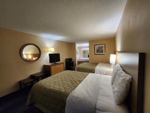 a hotel room with two beds and a mirror at Budget Host Inn in Henderson