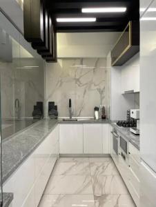 a kitchen with white cabinets and marble counter tops at Penthouse Împăratul Traian in Craiova