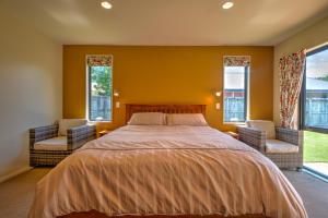 a bedroom with a bed and two chairs and windows at 20 Rippingale Road in Hanmer Springs