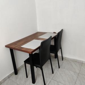 una mesa de madera con dos sillas negras alrededor en Agradable departamento para descanso o home office. en Cabo San Lucas