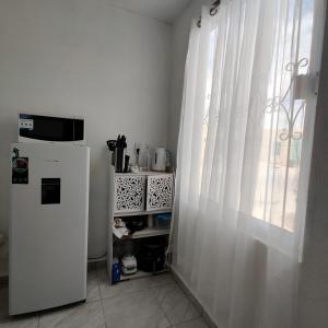 una cocina con nevera y una ventana con cortinas en Agradable departamento para descanso o home office. en Cabo San Lucas