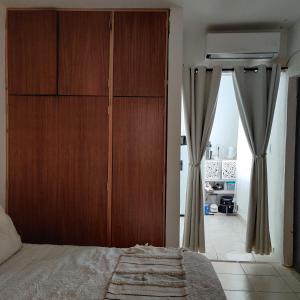 1 dormitorio con un gran armario de madera con cortinas en Agradable departamento para descanso o home office. en Cabo San Lucas