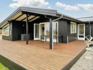 une maison noire avec une terrasse en bois dans l'établissement Holiday home Ølsted III, à Ølsted