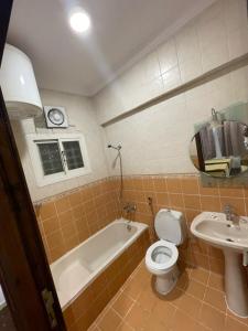 a bathroom with a tub and a toilet and a sink at فندق العز بيتي in Al Madinah