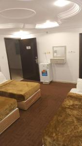 a room with two beds and a refrigerator at فندق العز بيتي in Al Madinah