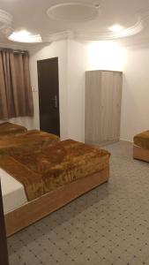 a bedroom with a large bed and a cabinet at فندق العز بيتي in Al Madinah