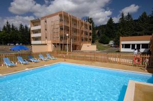 une grande piscine avec des chaises et un bâtiment dans l'établissement Résidence Goélia Le Sornin, à Autrans