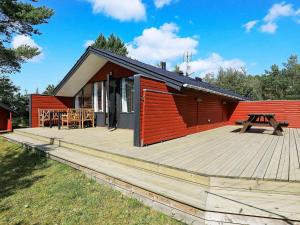 a cabin with a wooden deck and a picnic table at 6 person holiday home in Ålbæk in Ålbæk
