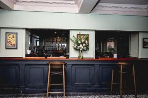 Eine Bar mit zwei Hockern und einer Blumenvase in der Unterkunft Thames Riviera Hotel, Sure Hotel Collection by Best Western in Maidenhead