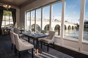 ein Esszimmer mit Tisch und Stühlen und Blick auf eine Brücke in der Unterkunft Thames Riviera Hotel, Sure Hotel Collection by Best Western in Maidenhead