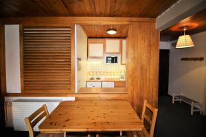 a dining room with a wooden table and a kitchen at Résidence Roches Rouges A - 2 Pièces pour 4 Personnes 971 in Tignes