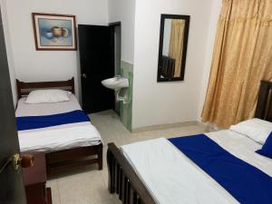 a bedroom with two beds and a sink and a mirror at HOSTAL OLAS CLUB DE NEGUANJE -TAYRONA in Santa Marta