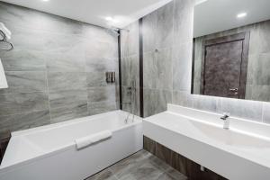 een witte badkamer met een bad en een wastafel bij Best Western Plus Batumi in Batoemi