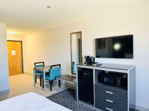 Habitación de hotel con cama, mesa y TV. en SureStay Plus by Best Western St. James Donaldsonville en Donaldsonville