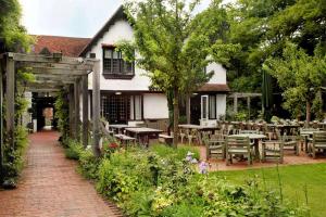 een tuin met tafels en stoelen en een gebouw bij The Olde Bell, BW Signature Collection in Marlow