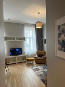 a living room with a flat screen tv and a chair at Hoffmann Rezidence in Rīga