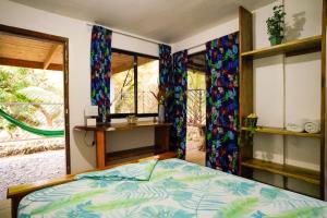 a bedroom with a bed and two windows at Hotel Swell Pavones in Pavones