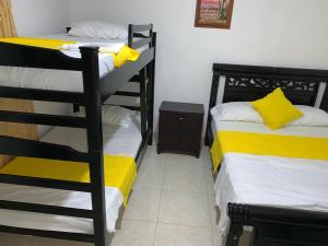 a room with two bunk beds with yellow sheets at HOSTAL OLAS CLUB DE NEGUANJE -TAYRONA in Santa Marta