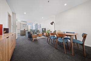 a dining room with a table and chairs and a living room at Glorious Central Canberra 1-Bed with Pool & Sauna in Canberra