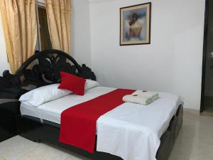 um quarto com uma cama com um cobertor vermelho e branco em HOSTAL OLAS CLUB DE NEGUANJE -TAYRONA em Santa Marta