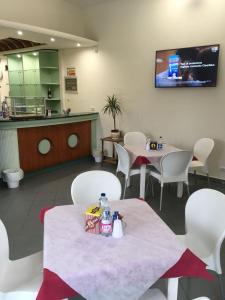 restauracja z białymi krzesłami i stołami oraz ladą w obiekcie Hotel Park Le Baleari w mieście Tirrenia