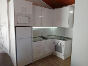 una cucina bianca con armadi bianchi e lavandino di Apartamento Isabel ad Ardales