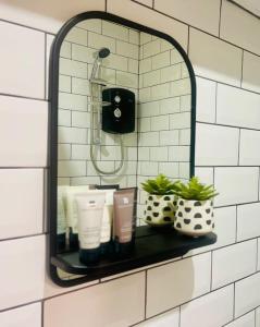 a mirror on a wall with a shelf with toiletries at New, unique, tiny house with garden in Wigston Magna