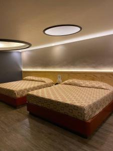 two beds are in a room with two lights at Hotel Gran Vía in Mexico City