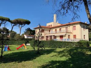 une grande maison avec une aire de jeux en face dans l'établissement Hotel Park Le Baleari, à Tirrenia