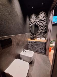 La salle de bains est pourvue de toilettes blanches et d'un lavabo. dans l'établissement Dark & Light rooms & luxury suites, à Catane