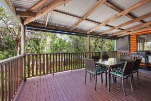 a wooden deck with a table and chairs on it at Lorikeet Patch in Peregian Beach