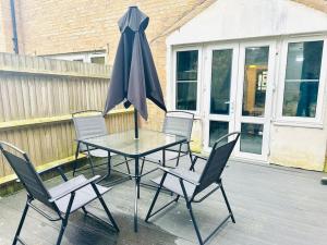 a table with chairs and an umbrella on a patio at The Esplanade Lodge-Free Parking in Strood