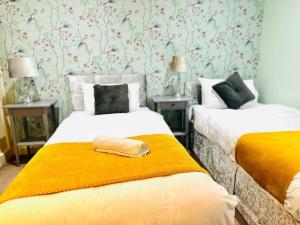 a bedroom with two beds with yellow blanket at The Esplanade Lodge-Free Parking in Strood