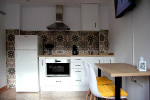 una cucina con armadi bianchi, tavolo e frigorifero di La casita de Fide a Molinaseca Altre 7 foto