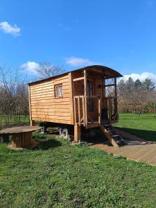 una pequeña casa de madera con porche y banco en Roulotte Ô Rêves Atypiques en Boucé