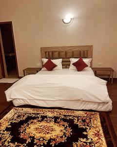 a bedroom with a white bed with red pillows and a rug at Own stay Chhaterpur in New Delhi