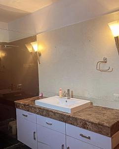 een badkamerbar met een witte wastafel en een spiegel bij Own stay Chhaterpur in New Delhi