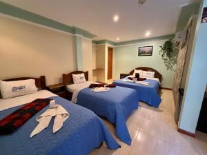 Habitación de hotel con 3 camas con sábanas azules en HOTEL MUEVETE POR VARGAS, en Catia La Mar