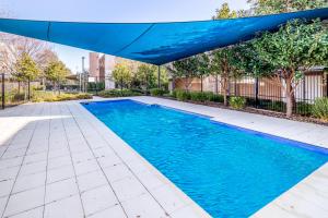 uma piscina com um guarda-chuva azul sobre ela em Exquisite Apartment with BBQ and Pool, near Shops em Phillip