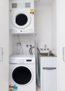 uma cozinha com uma máquina de lavar roupa e um lavatório em Exquisite Apartment with BBQ and Pool, near Shops em Phillip