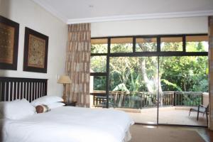 a bedroom with a bed and a large window at 14 Zimbali Chalets in Ballito