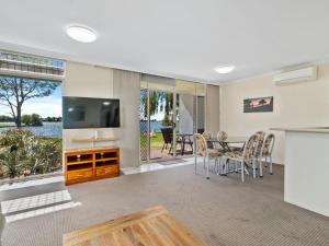 a living room with a television and a table with chairs at Yarrawonga Lakeside Apartment 23 in Mulwala