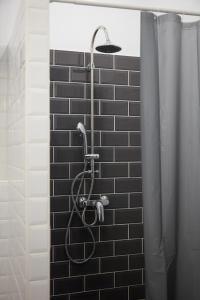a shower in a bathroom with a black tile wall at Springfield Kitty Kingdom in Budapest